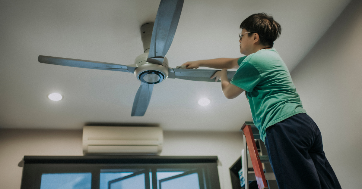 Woman cleaning a ceiling fan to reduce noise