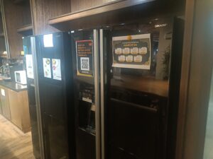 Large black Sharp fridge in a coworking space kitchen.