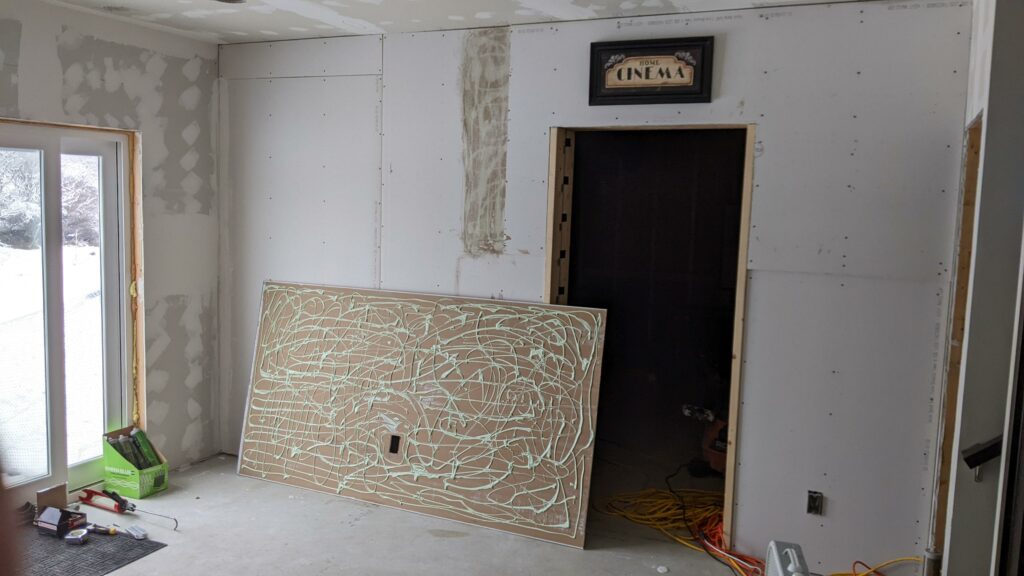 Green glue applied on a layer of drywall in a soundproofing project for a home theater.