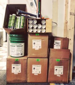 A large stock of Green Glue tubes and buckets.