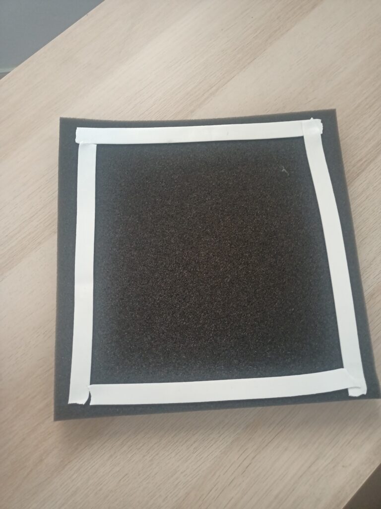 The back of an acoustic foam panel with double sided mounting tape used as adhesive.